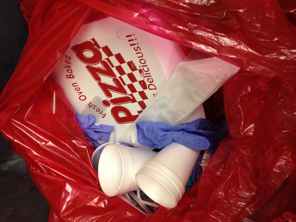 pizza box in a red garbage bag